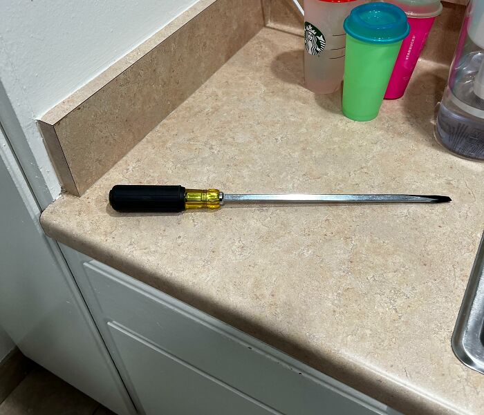 Large screwdriver on a kitchen counter, with cups nearby, illustrating a bad day scenario.