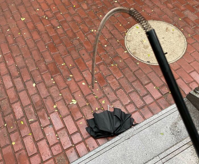 Broken umbrella on wet brick pavement, likely indicating a worse day for someone.