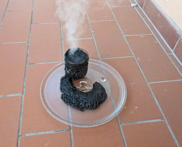 Burnt cup on a kitchen plate, steam rising, suggesting a person having a worse day.