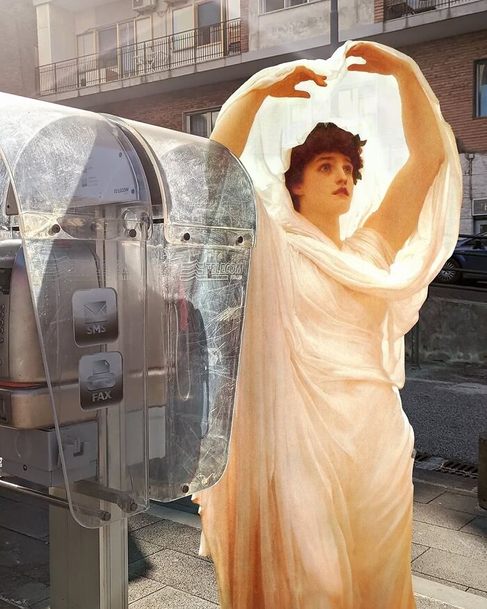Classical figure in a modern city street, blending art and environment with a vintage payphone.