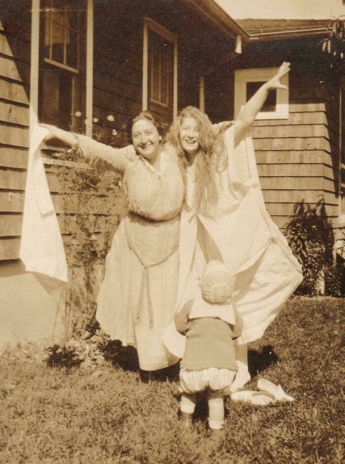 Mujeres y niño posando con vestidos antiguos en jardín, foto vintage que evoca imágenes históricas memorables.