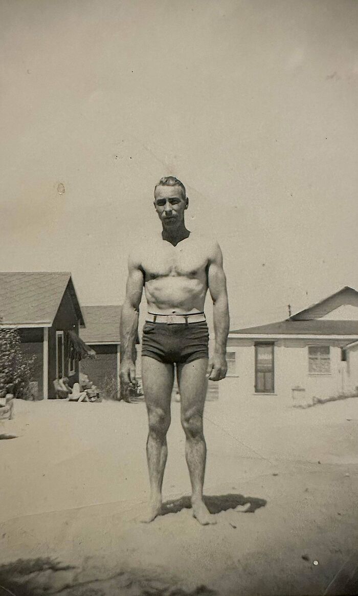 Man in vintage swim trunks standing outdoors, embodying beautiful and interesting old moments from the past.