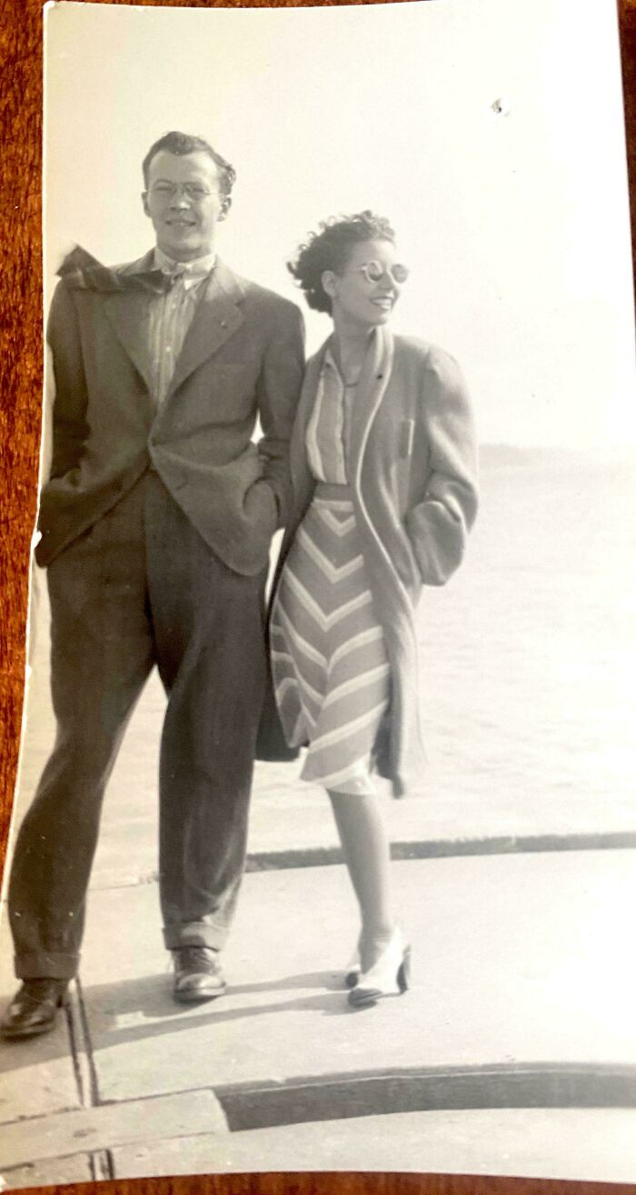 A couple in vintage clothing strolls by the sea, embodying interesting old pics that capture past moments.