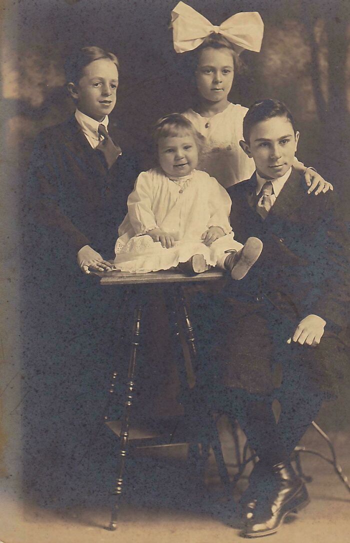 Vintage portrait of four children in formal attire, capturing an interesting moment from the past.