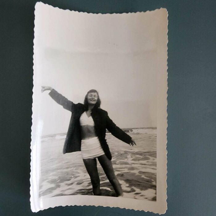 Woman joyfully posing at the beach in a vintage black and white photo, embodying beautiful and interesting old pics.