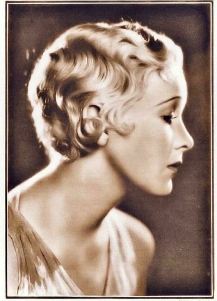 Mujer de décadas pasadas en retrato en sepia mostrando peinado clásico y expresión serena, imagen elocuente histórica.