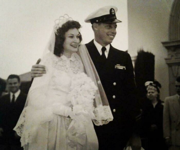 Old photo of a smiling bride and groom in uniform, capturing a beautiful moment from the past.