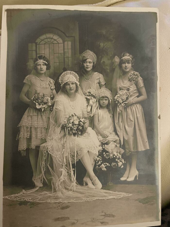Foto en blanco y negro de mujeres con vestidos antiguos posando en una boda, reflejando fotos de hace décadas.