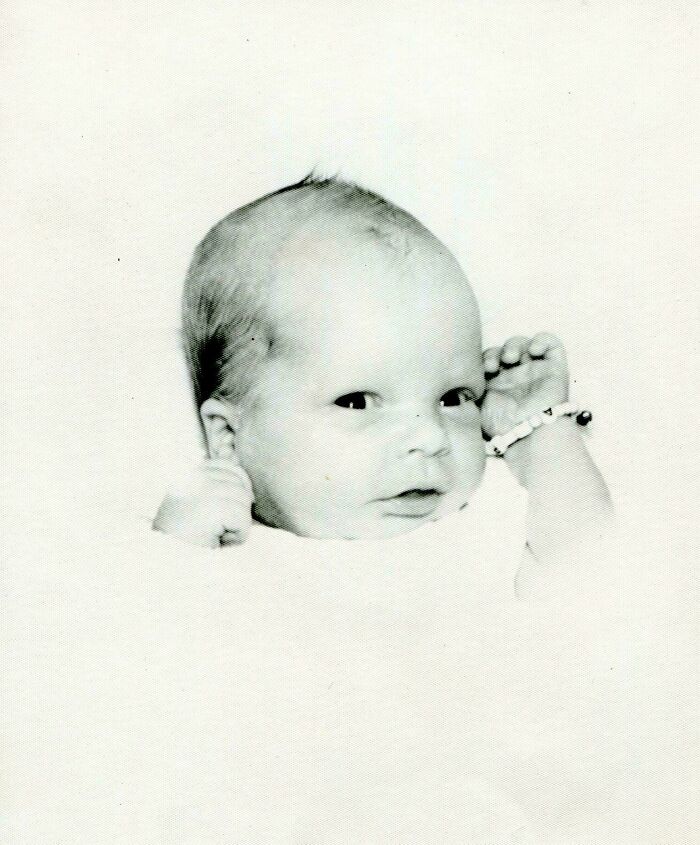 Old photo of a newborn with a hospital bracelet, showcasing a beautiful moment from the past.