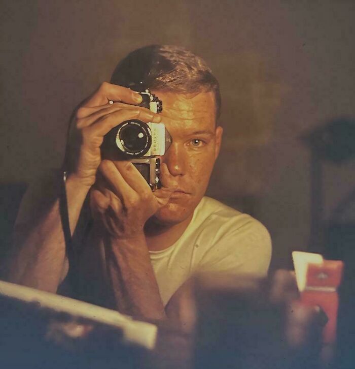 Man in a vintage setting taking a photo with a classic camera, capturing historical moments.