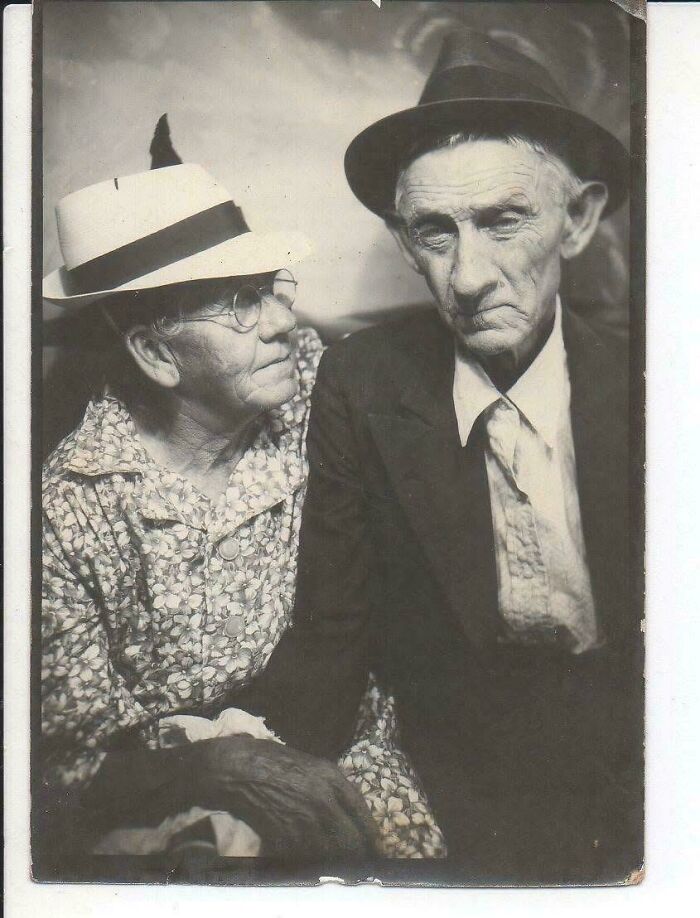 An elderly couple in vintage attire, captured in a nostalgic black-and-white portrait.