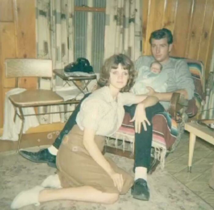 Vintage photo of a seated man holding a baby, with a woman kneeling beside them, capturing a beautiful moment in time.