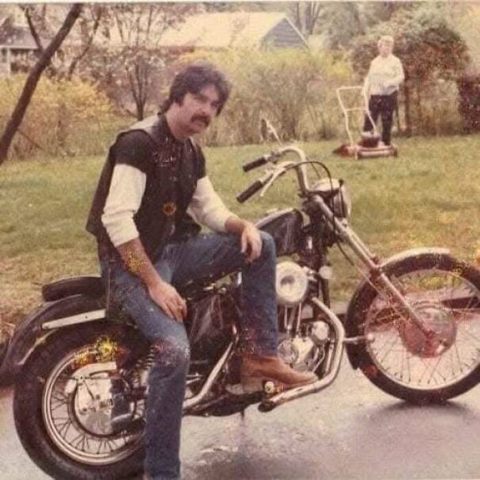 Man on a vintage motorcycle in a backyard, capturing a moment from the past.