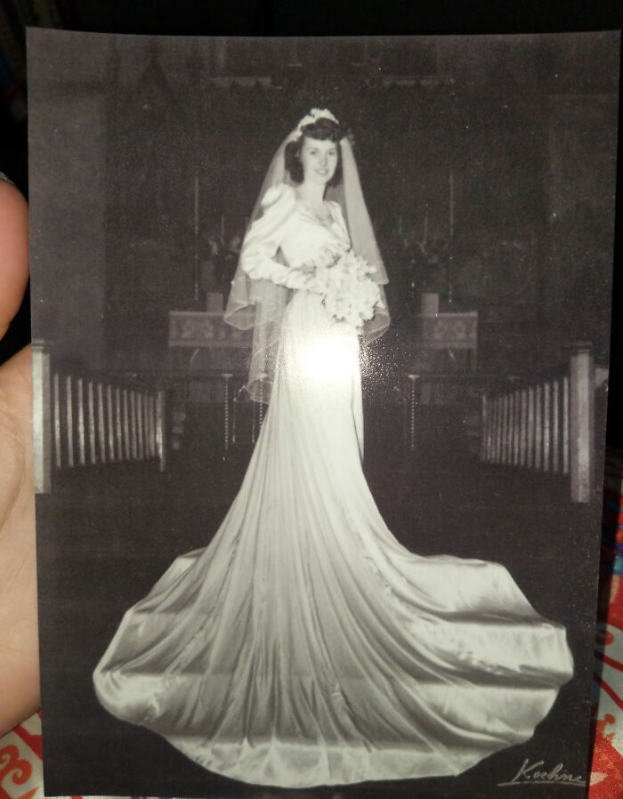 Vintage bride in a long, flowing gown and veil, holding a bouquet, standing in church setting, capturing the past.