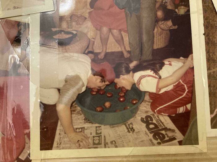 People bobbing for apples at a lively indoor gathering, capturing the essence of beautiful and interesting old pics.