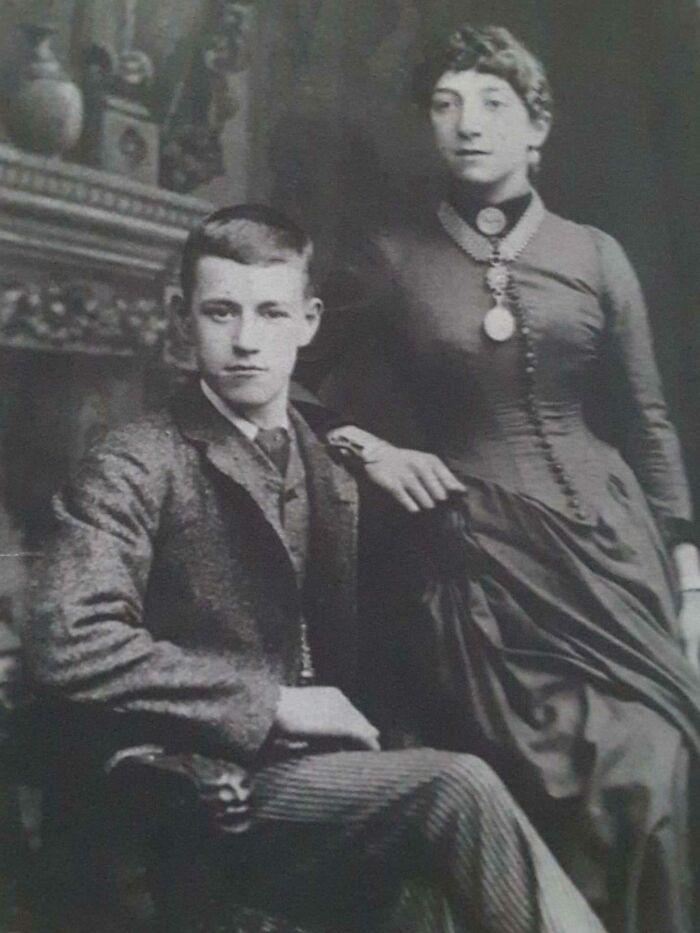 Vintage photo of a seated man and standing woman in period attire, showcasing beautiful old fashion styles.