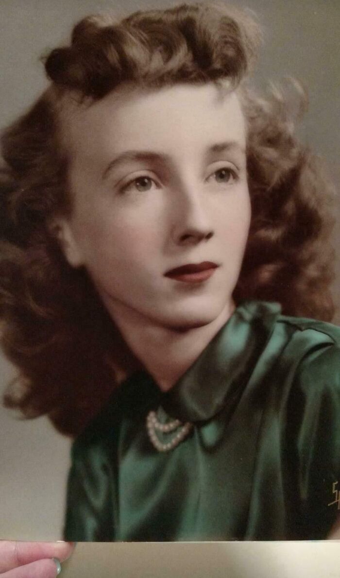 Vintage photo of a woman with wavy hair in elegant attire, showcasing beautiful style from the past.