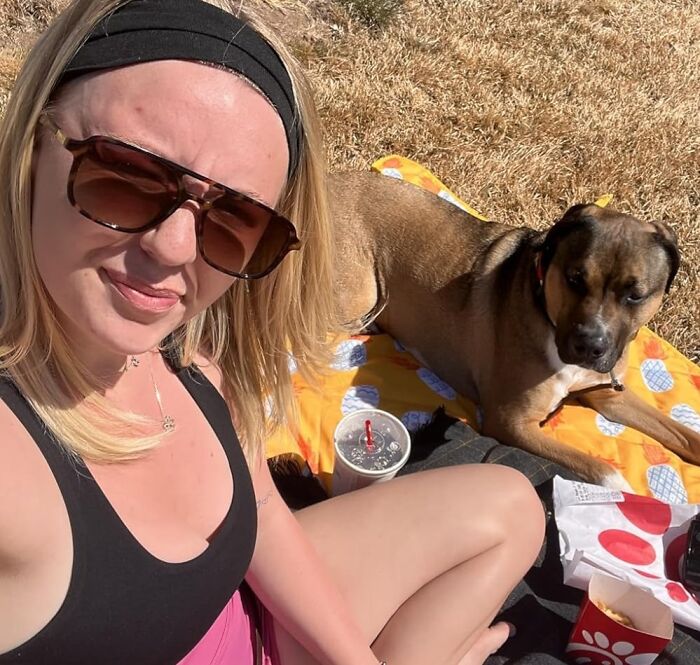 Woman enjoying a sunny picnic with her dog, featuring popular products from Amazon's Spring Sale.