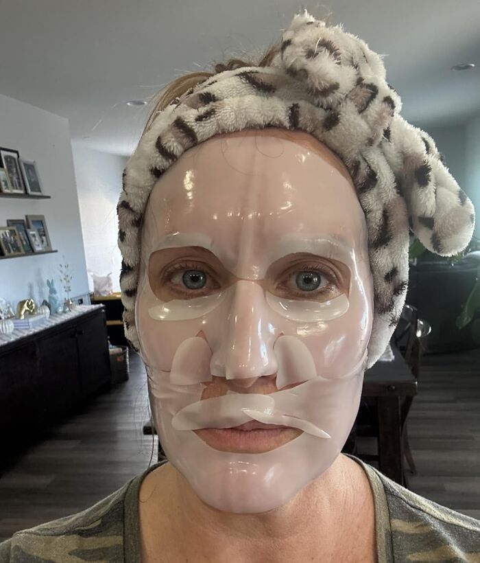 Woman wearing a hydrogel face mask from Amazon's spring sale with a leopard print headband in a cozy home setting.