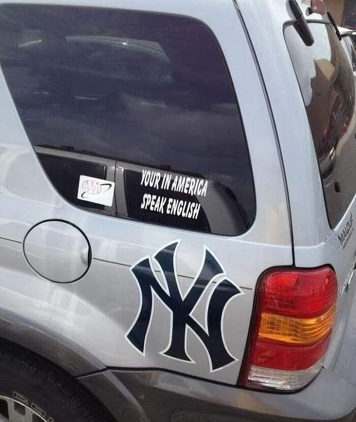 Car with sticker showing humorous language fail, featuring Yankees logo.