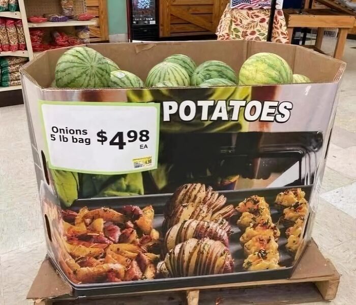 Watermelons in a box labeled for potatoes with a sign pricing onions, showcasing a confidently incorrect store display.
