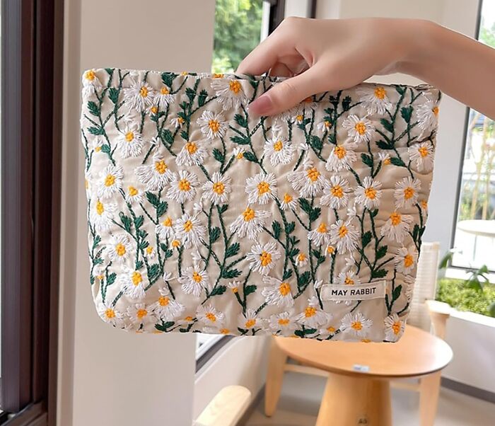 Hand holding an embroidered floral pouch with daisies, one of the top Amazon haul finds trending online.