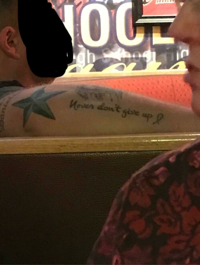Tattoo fail showing a misspelled phrase on a forearm with colorful star designs in a casual indoor setting.