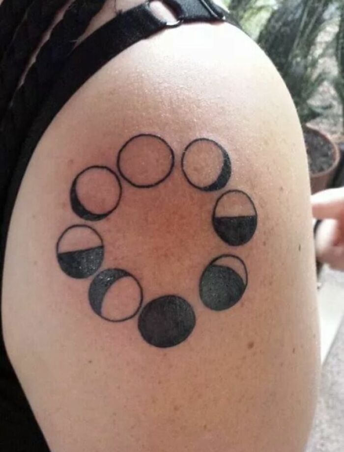 Tattoo fail of moon phase design with inconsistent shading on upper arm, showcasing a wild tattoo fail mistake.