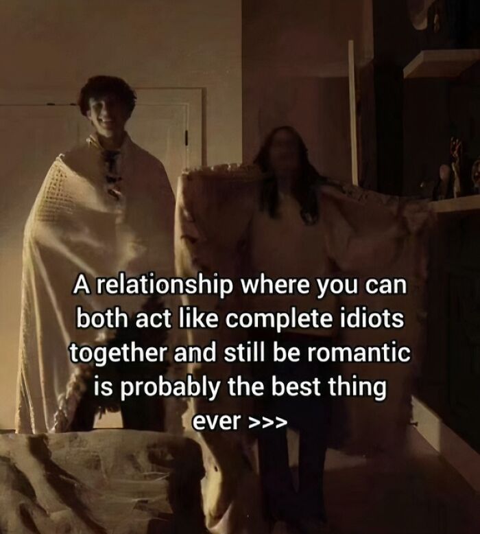 Couple wrapped in blankets laughing together with caption about love and romance.