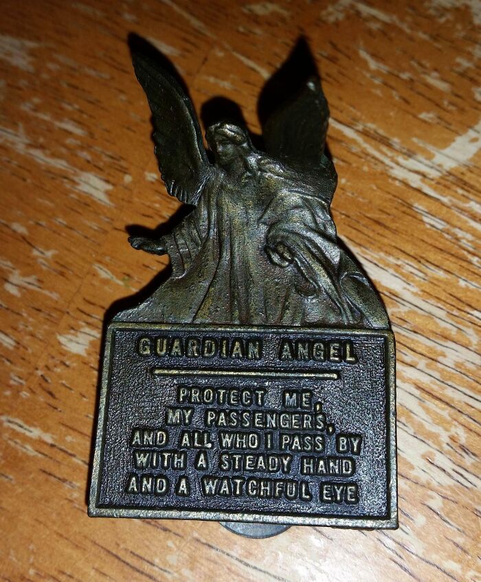Metallic guardian angel talisman with prayer on a wooden table.