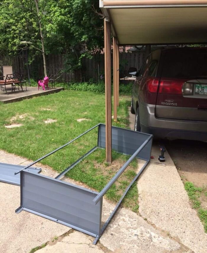 SUV parked beside a collapsed metal structure on a lawn under a carport.