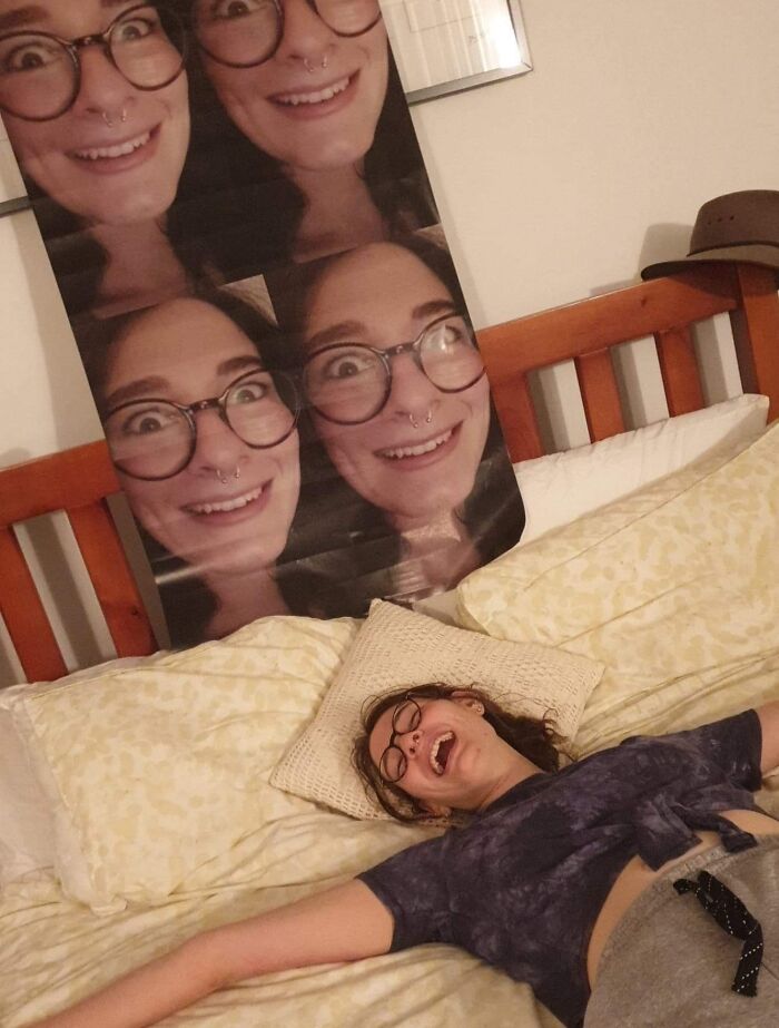 Person laughing on bed below humorous poster of own face, exemplifying a worse day scenario.