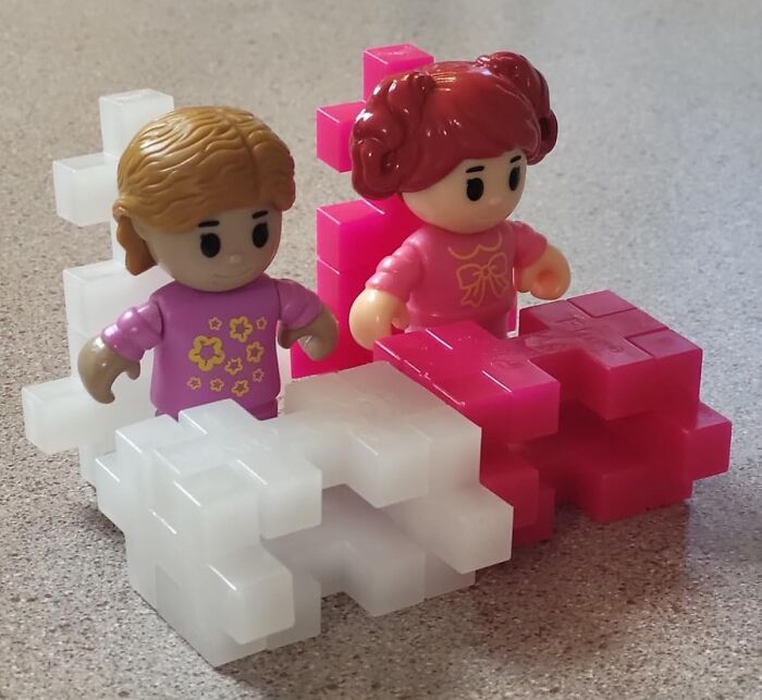 Two toy figures playing with interlocking block toys kids genuinely can't get enough of on a textured surface.