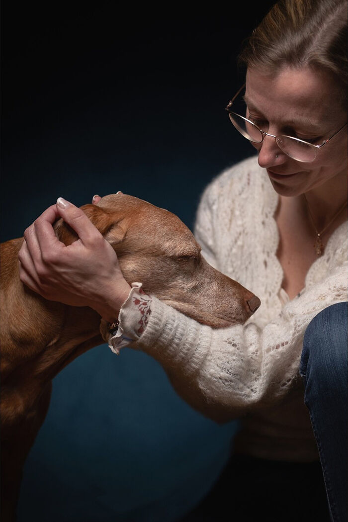 A woman gently embraces a hunting dog, showcasing art with purpose in a heartfelt moment.