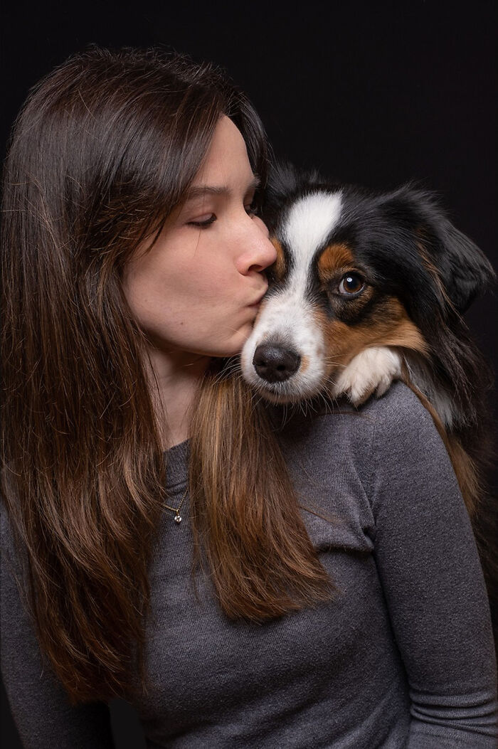 Elke Vogelsang portrait of a woman kissing a hunting dog against a dark background.