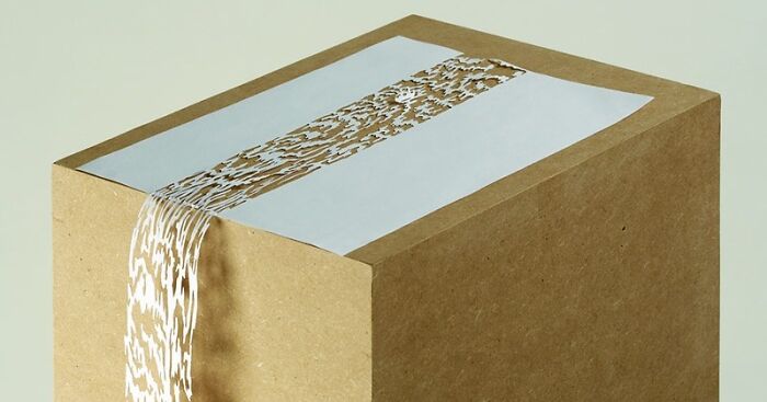 Paper art sculpture by Peter Callesen featuring intricate cut-out detail on a cardboard block.