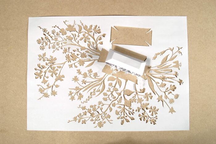 Intricate paper art mini world featuring delicate cut-out floral designs by Peter Callesen.