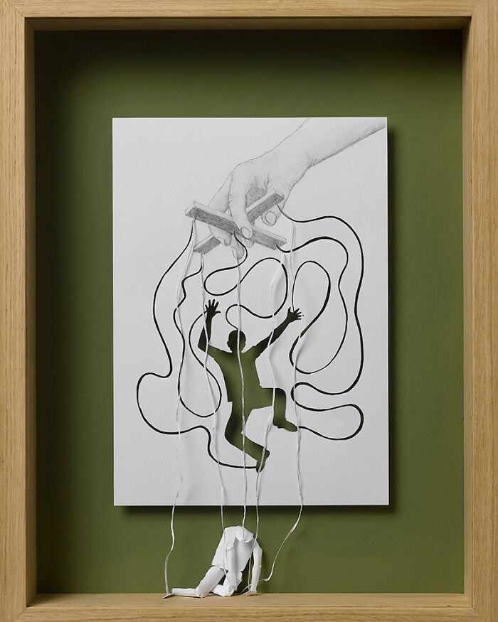Paper art by Peter Callesen featuring a cutout figure and strings in a wooden frame, showcasing intricate design.