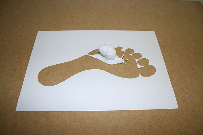 Paper art by Peter Callesen featuring a cut-out footprint with a delicate paper sculpture emerging.