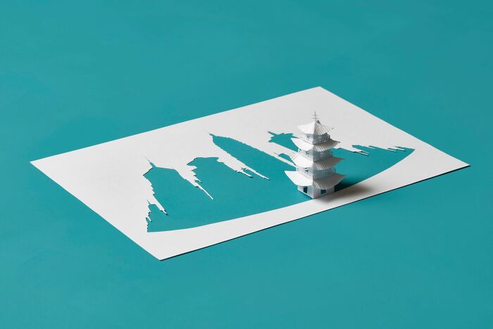 Paper art by Peter Callesen featuring a 3D miniature pagoda emerging from a paper sheet.