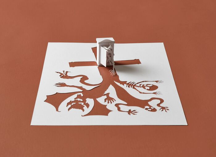 Intricate paper sculpture by Peter Callesen depicting a complex tree design emerging from a sheet.