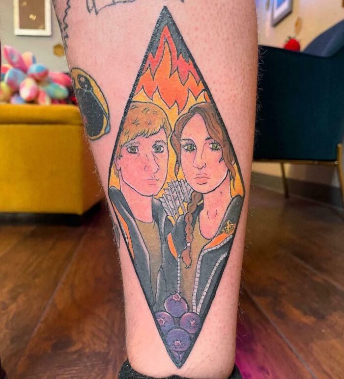 Tattoo fail of two cartoon characters with flames in the background on a person's leg, a wild tattoo fail example.