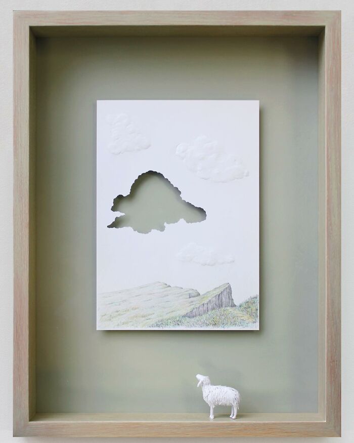 Paper art by Peter Callesen featuring a cloud cutout and a paper sheep in a landscape scene.