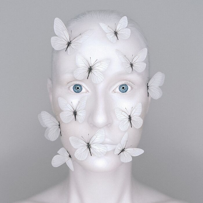 Surreal self-portrait of an artist with white butterflies on her face, using Photoshop to create dreamy visuals.