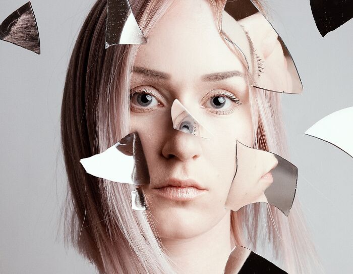 Surreal self-portrait of an artist using Photoshop, featuring fragmented reflections and a dreamy expression.