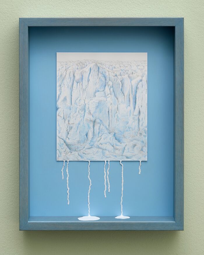 Paper art mini world in a blue frame by artist Peter Callesen, featuring intricate details and flowing paper elements.