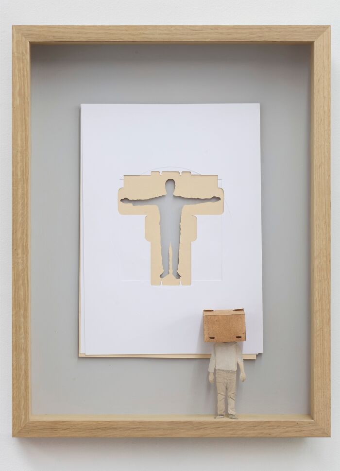 Miniature paper art by Peter Callesen featuring a cut-out human figure in a frame with a small paper person.