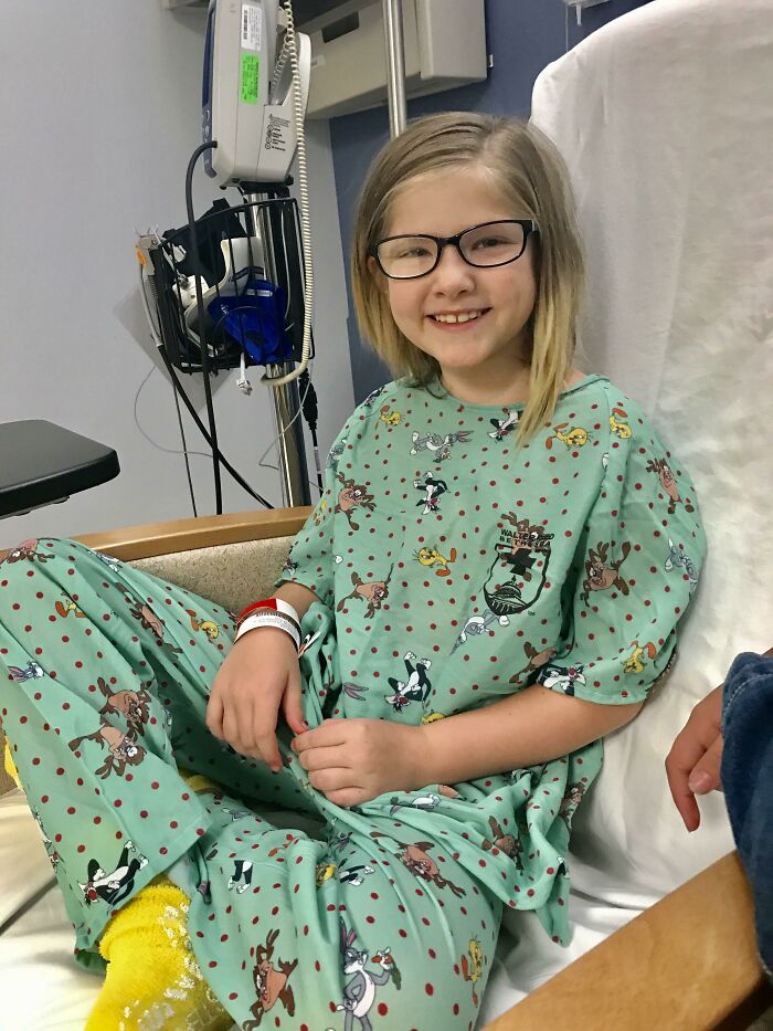 Niña sonriente en hospital vistiendo pijama de dibujos animados, mostrando un momento positivo y conmovedor para recobrar la fe.