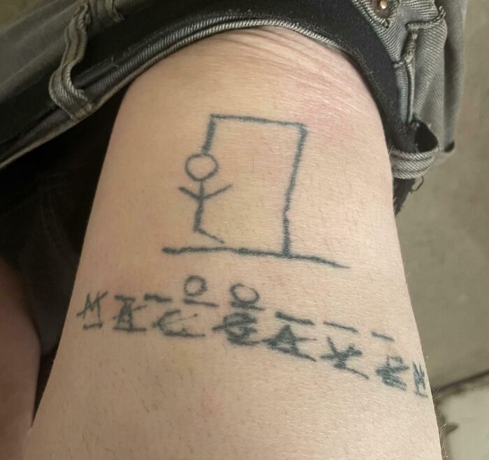 Stick figure hangman tattoo with unclear symbols below, showcasing one of the wild tattoo fails now a permanent problem.