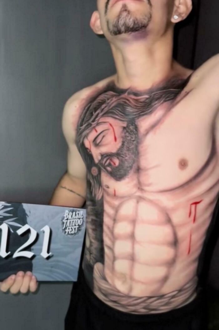 Man showing wild tattoo fail of a distorted face and muscles covering his chest at Brasil Tattoo Fest.